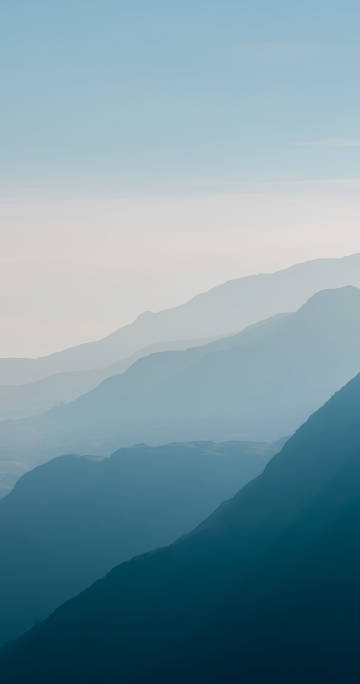 淡蓝天空下的山峦景色手机壁纸